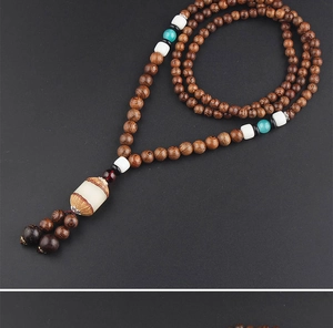 Detailed close-up of dark brown wooden beads with turquoise accents and a barrel pendant