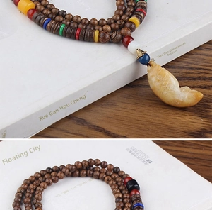 Detail of ethnic style necklace with multi-layer wooden beads and a stone fish pendant