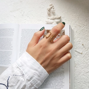 Close-up of golden abstract wave ring featuring fluid sculptural design and open band