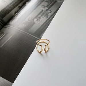 Detail of artistic gold face ring showing dual band design and abstract silhouettes