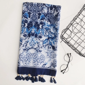 Detail of bohemian cotton linen scarf featuring blue floral patterns and wooden bead tassels