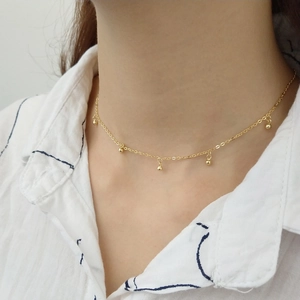 Close-up of a 925 sterling silver gold beaded necklace worn on a striped shirt
