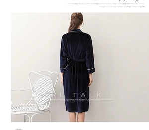 Detail of dark blue velvet bathrobe featuring white piping on sleeves and belted waist