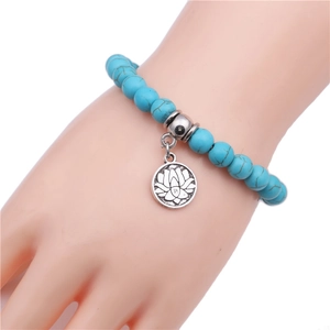 Sky blue turquoise beaded bracelet with silver lotus pendant on white background