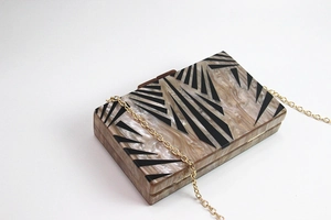 Detail of geometric acrylic evening clutch with marble pattern and gold chain strap