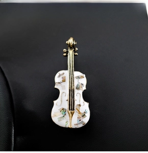 Detailed close-up of violin brooch with white enamel and shimmering shell inlays