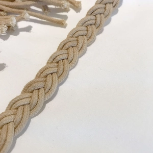 Gros plan sur la corde en coton tressé beige faite main avec détails de pompons et tissage