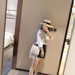 Détail d'un sac en macramé blanc avec des motifs de losanges tissés et de longues franges