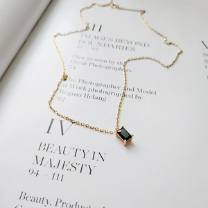 Detail of a 925 silver gold necklace with a rectangular black gem pendant on an art magazine