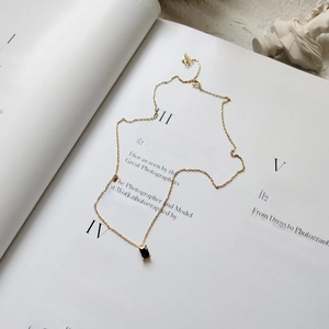 Macro detail of a 925 sterling silver golden chain with a black rectangular pendant on a book