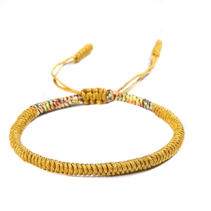 Detailed shot of handmade braided golden knot bracelet with colorful ethnic thread accents