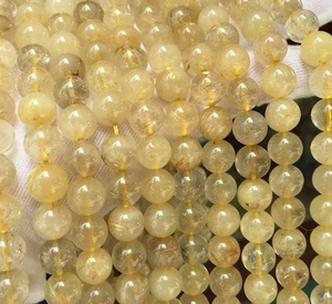 Macro shot of 8mm natural golden rutilated quartz beads with needle-like inclusions
