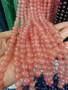 Macro view of a pink strawberry quartz bead pendant on a stainless steel chain
