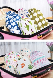 Patterned linen-cotton drawstring bags organized inside a pink suitcase for travel storage