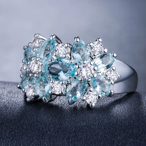 Vista macro di un anello a fiore con pietre marquise azzurre e zirconi bianchi