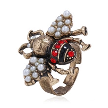 Macro detail of a baroque bee ring with white pearls and red crystal embellishments