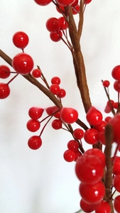 Macro detail of glossy red artificial berries on simulated dark brown branches