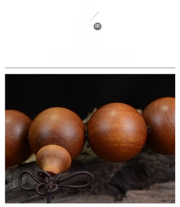 Macro detail of polished dark brown sandalwood beads with natural wood grain and woven knot