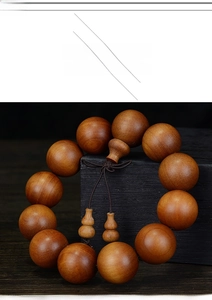 Close-up of polished dark sandalwood beads with a decorative Chinese knot and gourd pendants