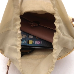 Handmade straw bucket bag with drawstring liner showing spacious interior for tablet and wallet