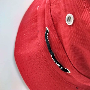 Detail of red canvas bucket hat showing SPORT drawstring and breathable air eyelets