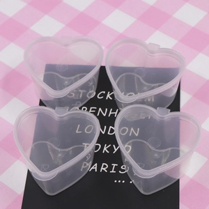 Set of four heart-shaped transparent plastic containers with lids on checkered background