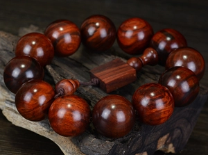 Détail macro de perles bouddhistes en bois de rose foncé sur socle en bois vintage