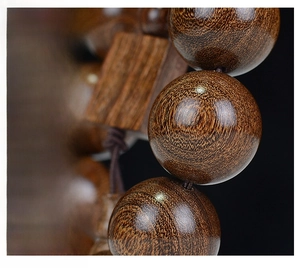 Macro shot of polished sandalwood beads with golden grain texture and wooden accent
