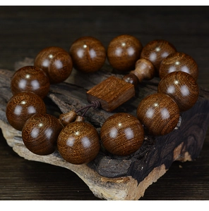 Macro detail of sandalwood beads with golden wavy texture on a natural bark base