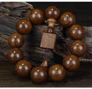 Macro detail of sandalwood prayer beads showing natural wood grain on a wooden background