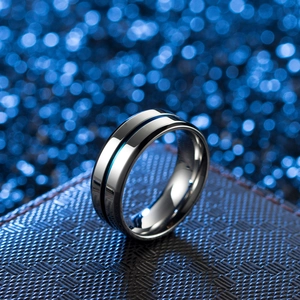 Polished stainless steel ring with blue groove detail on a dark textured surface