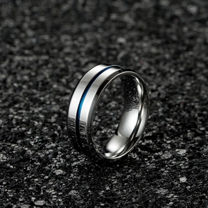 Close-up of a silver stainless steel ring featuring a central blue groove on a dark surface