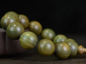 Makroaufnahme natürlicher grüner Sandelholzperlen mit feiner Maserung und Flaschenkürbis