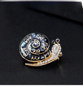 Macro view of snail brooch with gold plating, sparkling rhinestones and enamel finish