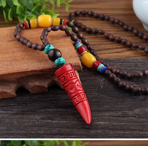 Close-up of ethnic necklace with wooden beads and a red engraved pendant on a wood surface