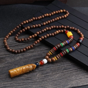Ethnic wood bead necklace with yellow carved pendant on dark rustic wooden background