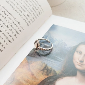 Detail of vintage S925 sterling silver ring with oval white opal stone on an art book