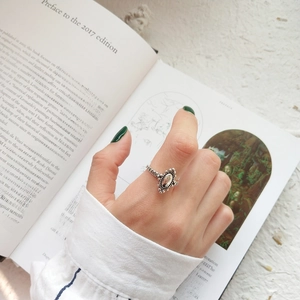 Close-up of vintage style silver oval ring worn by a model holding an aesthetic book