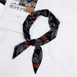 Dettaglio del nastro per capelli in seta nera con stampa floreale e foglie geometriche