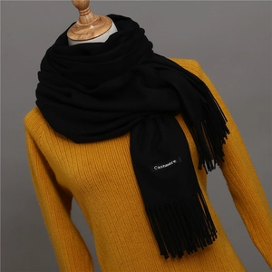 Close-up of black cashmere scarf with thick tassels and a visible Cashmere fabric label