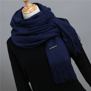 Detail of navy cashmere-feel scarf featuring soft fringe and stitched brand label