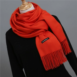 Close-up of vibrant orange-red cashmere-feel scarf featuring soft fringe details
