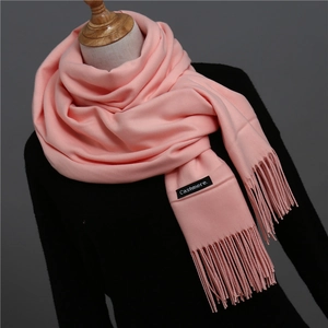 Detail of pink cashmere scarf featuring soft knit texture, fringes, and woven brand label