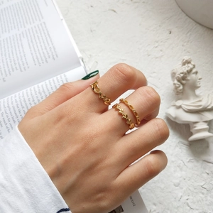 Detailed view of three-piece gold ring set with Love, leaf and chain designs on a hand