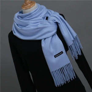 Detail of light blue cashmere scarf showing woven texture, tassel fringe and brand label