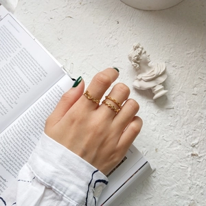Detail of gold LOVE letter rings and minimalist stackable bands on a model's hand