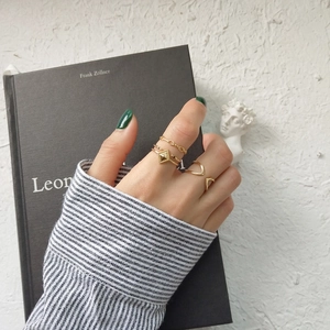 Close-up of three-piece minimalist gold ring set featuring geometric and chain designs