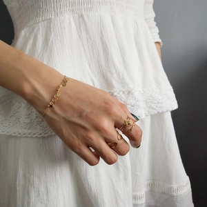 Detail of gold-plated silver bracelet with round charms and layered rings for women