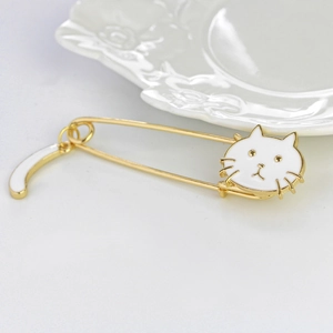 Detailed view of a cute white cat safety pin brooch with a dangling metal tail feature