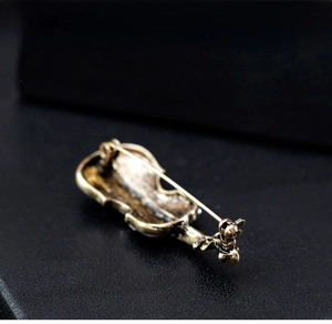 Detailed back view of vintage cello brooch with shell inlay and sturdy metal safety pin